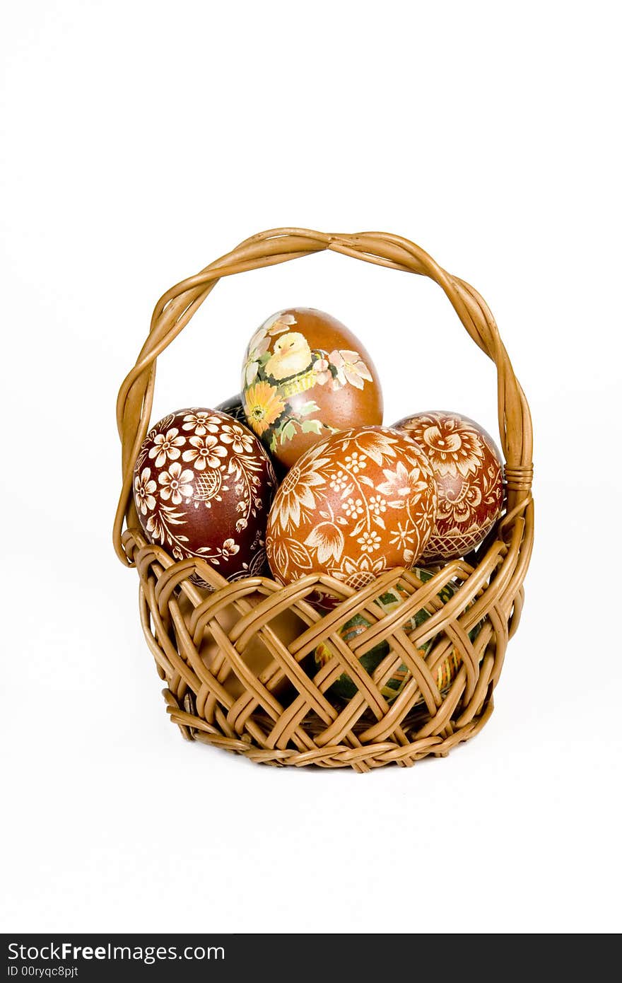 Wicker basket full of easter eggs on white background