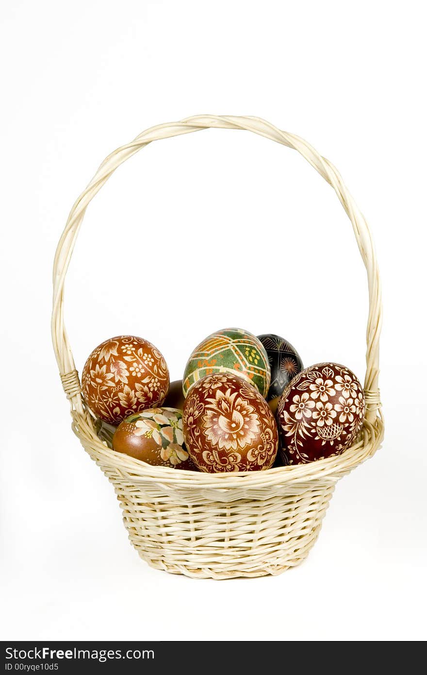 Wicker basket full of easter eggs on white background