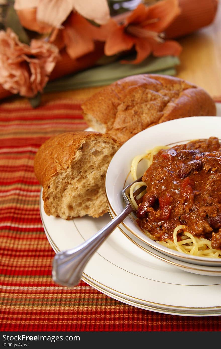 Western style meat and bean chili served on top of spaghetti with a side of rustic wheat bread. Western style meat and bean chili served on top of spaghetti with a side of rustic wheat bread.