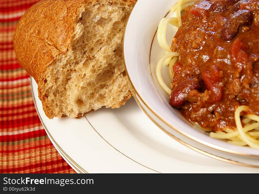 Course whole wheat bread next to bowl of homemade chili