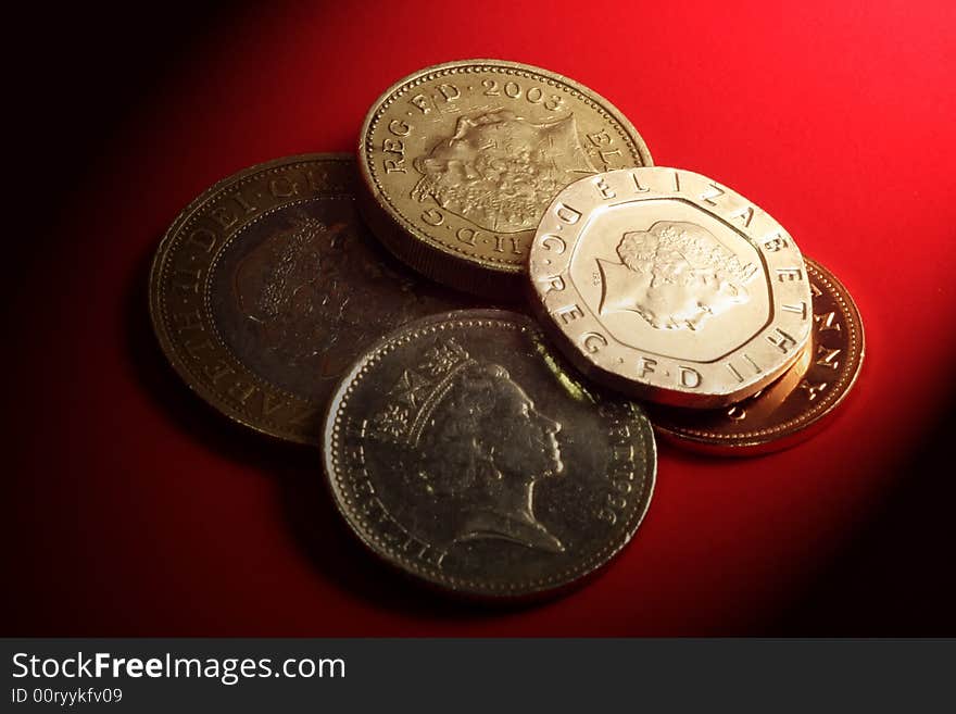 British currency coins on red background with shadows. British currency coins on red background with shadows