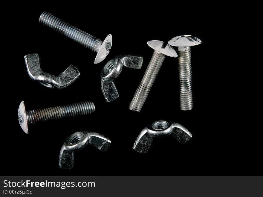 A group of wing nuts and bolts, isolated on a black background.