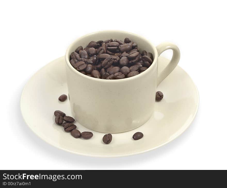 Coffee beans in creme cup with a few coffee beans on saucer. Coffee beans in creme cup with a few coffee beans on saucer.