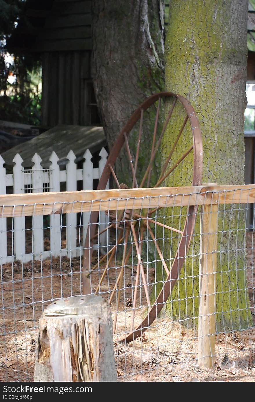 Rusty waggon wheel against a country fence. Rusty waggon wheel against a country fence