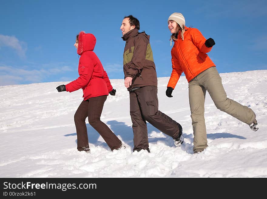 Three friends walk on snow on hillside