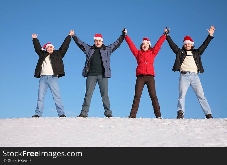 Four friends greetings on snow  in santa claus hats. Four friends greetings on snow  in santa claus hats