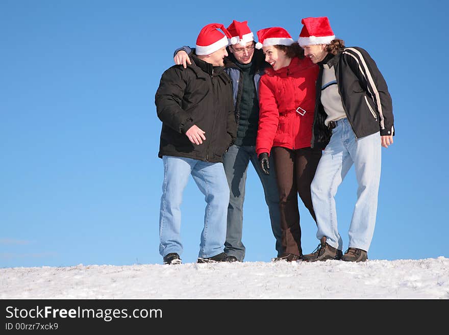 Four friends talk on snow in santa claus hats. Four friends talk on snow in santa claus hats