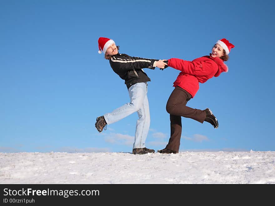 Couple dance on  snow hill in santa claus hats 2