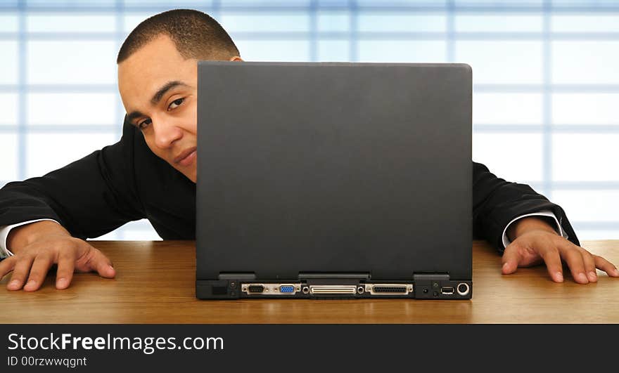 Business man playing hide and seek behind his laptop in his office because of boredom. Business man playing hide and seek behind his laptop in his office because of boredom