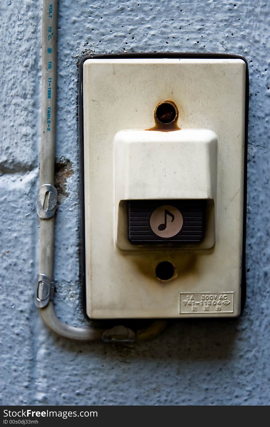 A dirty looking door bell buzzer on a wall