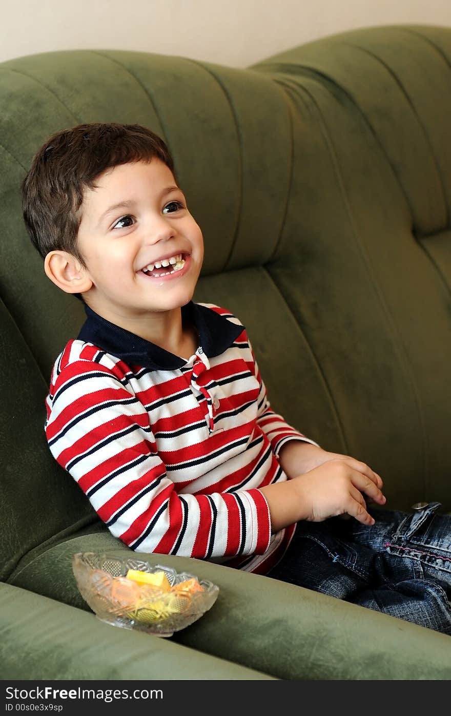 Little boy laughing sitting on sofa