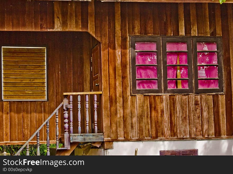 A wooden building with three pink windows