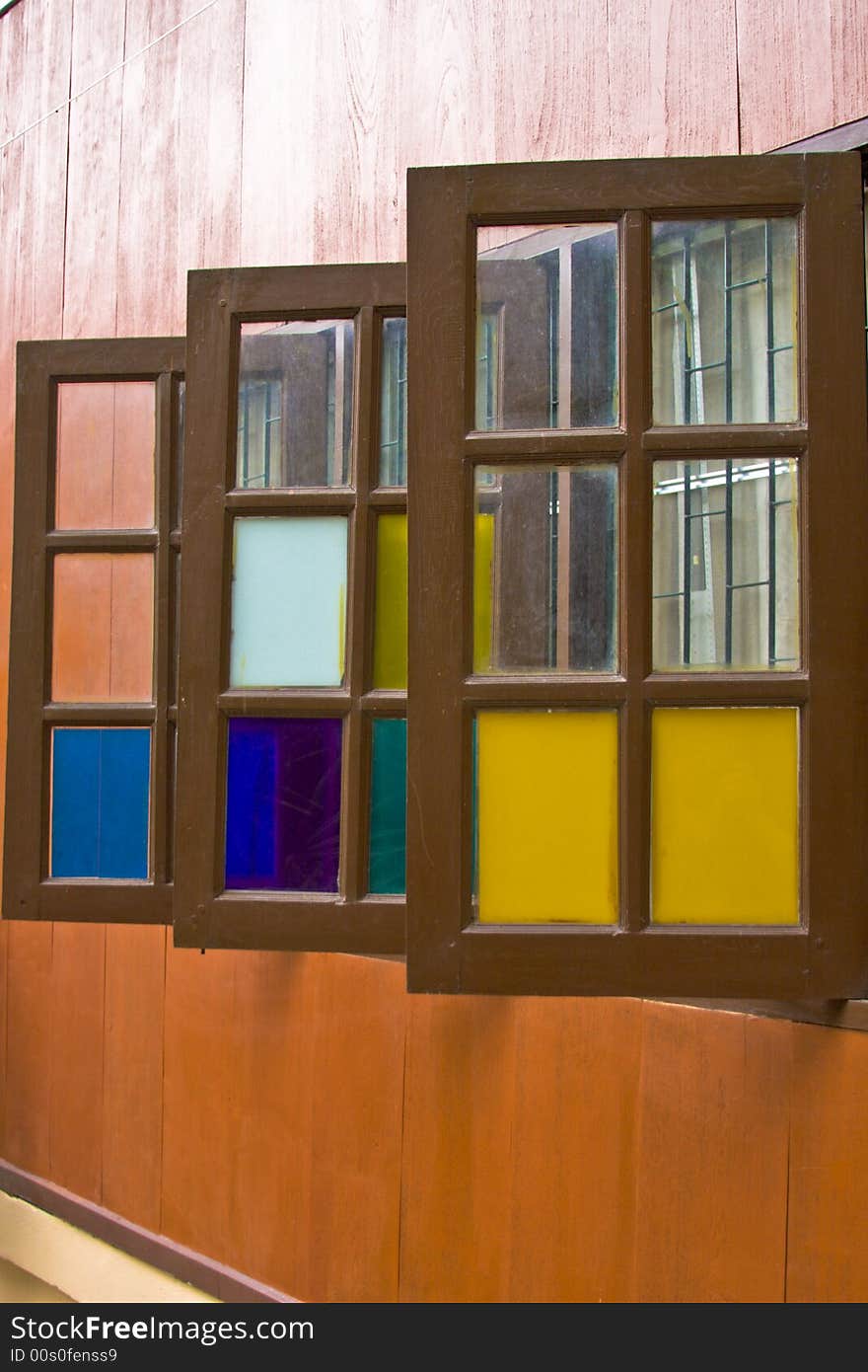 A wooden building with three colorful windows