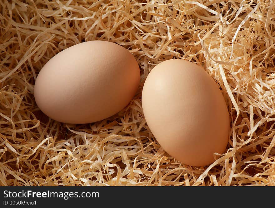 Two chicken eggs on straw.