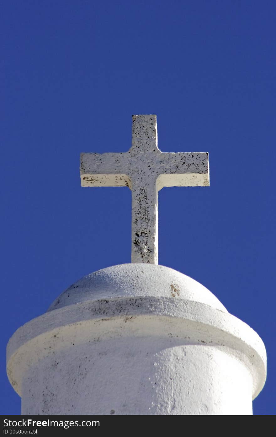 White cross on a chapel against a blue sky in Portugal