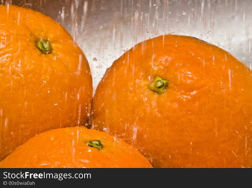 Lots of water drops falling on three oranges. Lots of water drops falling on three oranges
