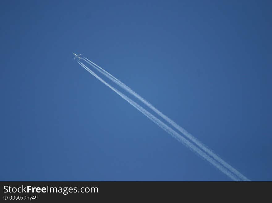 Airplane in the blue sky with condensated exhaust