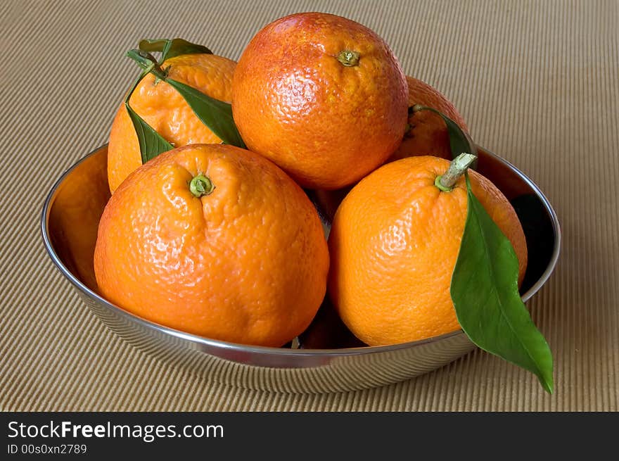 Five healthy oranges on a metallic plate