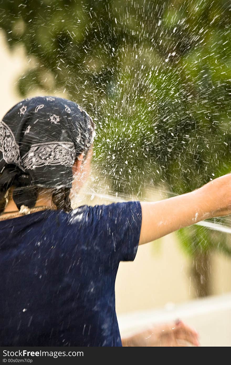 A girl gets sprayed in the face with water from a hose. A girl gets sprayed in the face with water from a hose