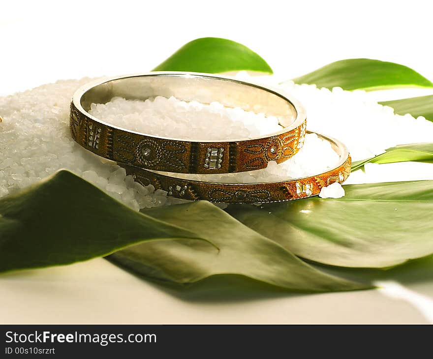 Two bracelets and bath salt on a green leaf