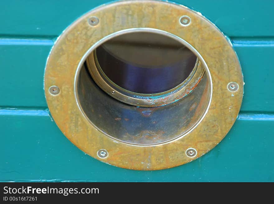 Brass porthole in the hull of a timber yacht.