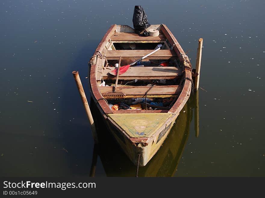 Old wooden boat beside pier with  oar