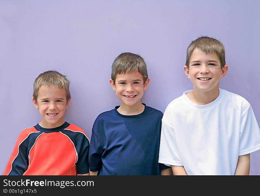 Three Brothers Posing Against a Purple Wall