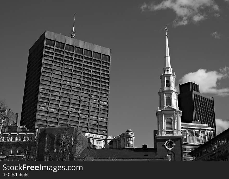 Downtown Boston showing the clock tower and steeple of Park Street Church surrounded by more modern buildings. Downtown Boston showing the clock tower and steeple of Park Street Church surrounded by more modern buildings