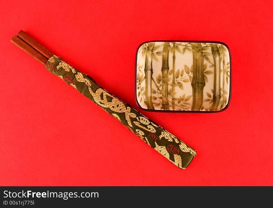 Bamboo design on a Japanese sushi bowl against red background with chopsticks. Bamboo design on a Japanese sushi bowl against red background with chopsticks