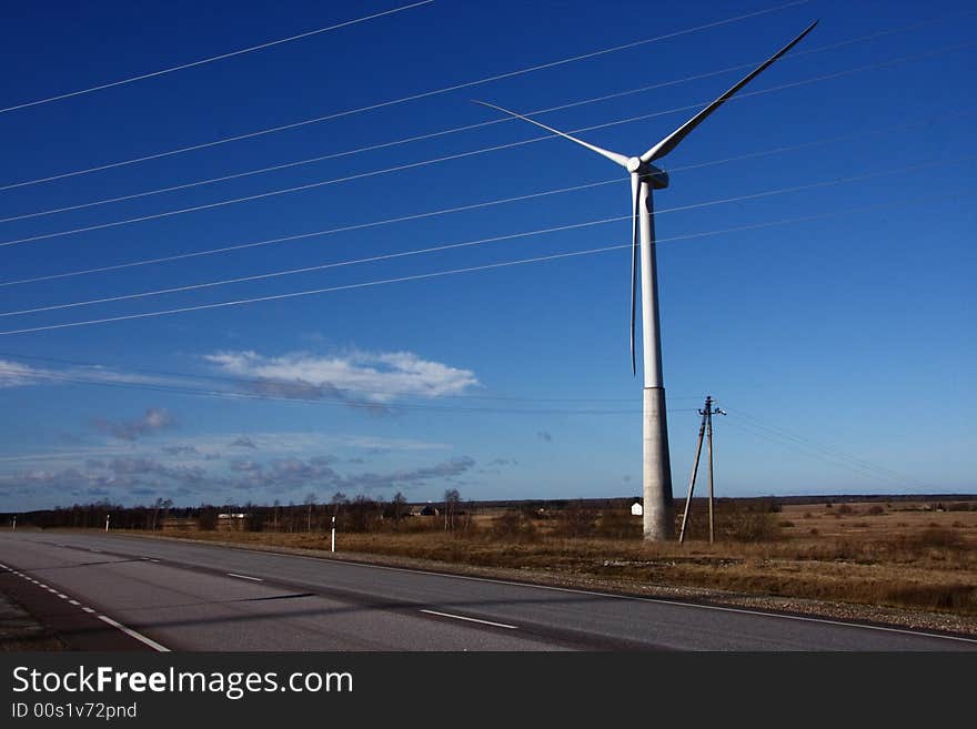 Windmill turbine behind electric lines generating power