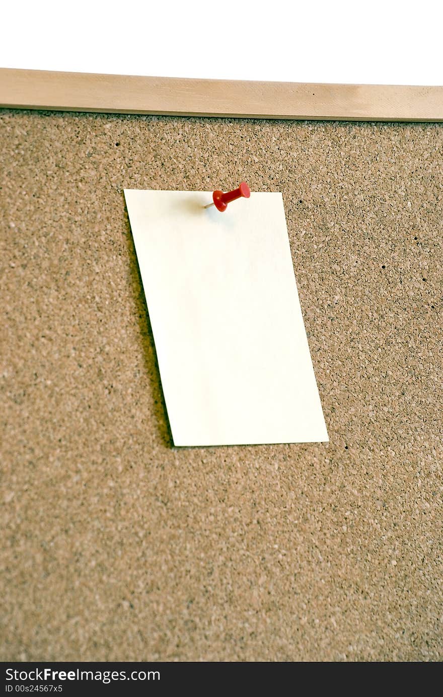 A close-up of a note page is attached to the board with  red pin. A close-up of a note page is attached to the board with  red pin