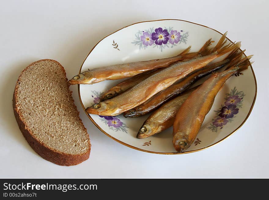 Smelt on a plate and a piece of rye bread. Smelt on a plate and a piece of rye bread