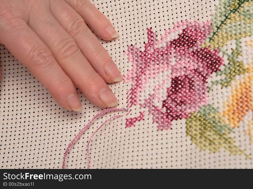 Woman embroidering a beautiful pink rose. Woman embroidering a beautiful pink rose