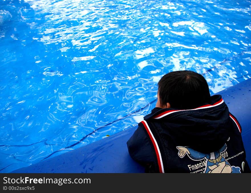 A Chinese kid stands looking into the blue clear glittering cleanpeaceful ,glittering water,.The water facea is the reflection of the blue,azure sky . A Chinese kid stands looking into the blue clear glittering cleanpeaceful ,glittering water,.The water facea is the reflection of the blue,azure sky .