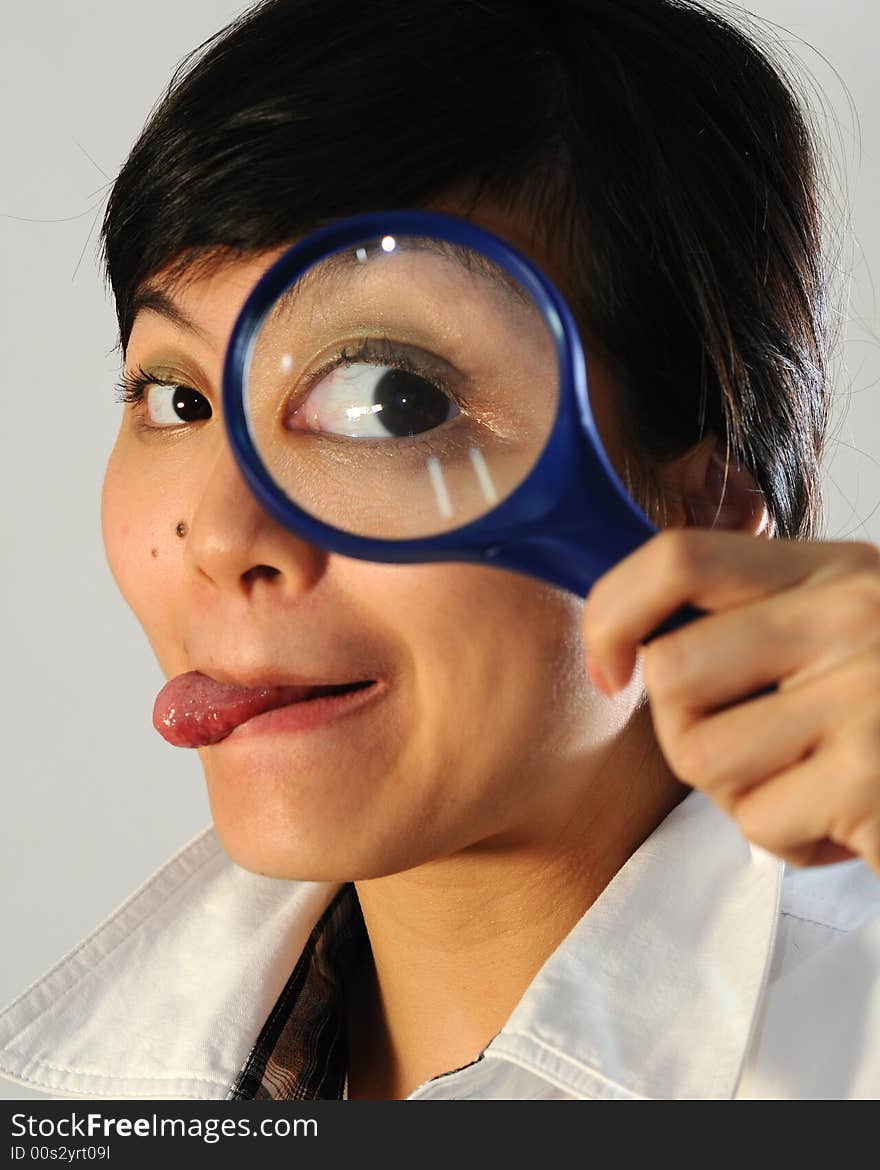 A curious asian lady looking through the magnifying glass. A curious asian lady looking through the magnifying glass