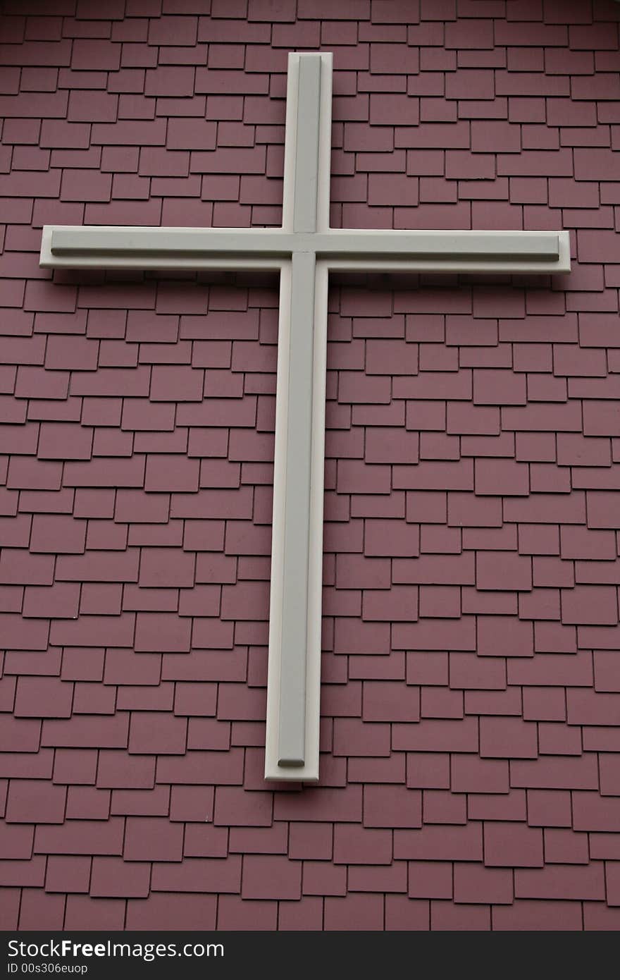 Cross over colored layered shingles on church building.