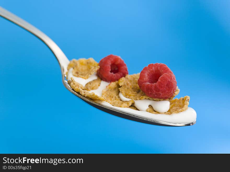 Corn flakes on the spoon with milk over a blue background