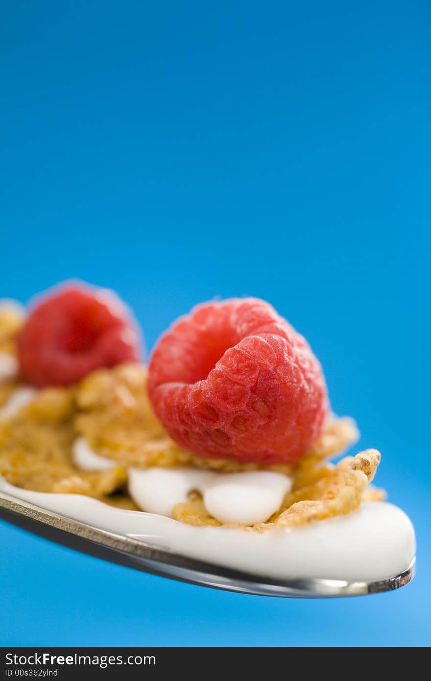 Macro of corn flakes on the spoon with milk over a blue background