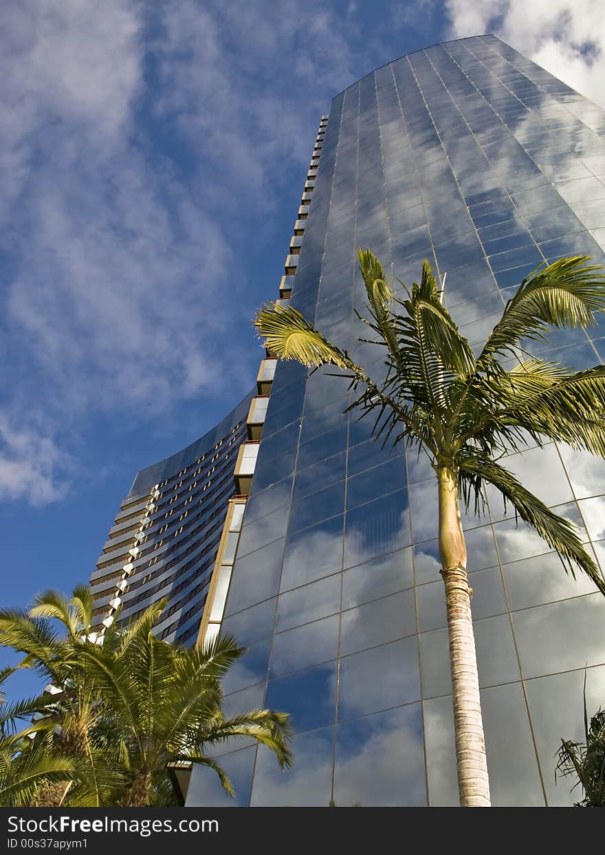 Glass skyscraper reflects sky with clouds in tropics. Glass skyscraper reflects sky with clouds in tropics