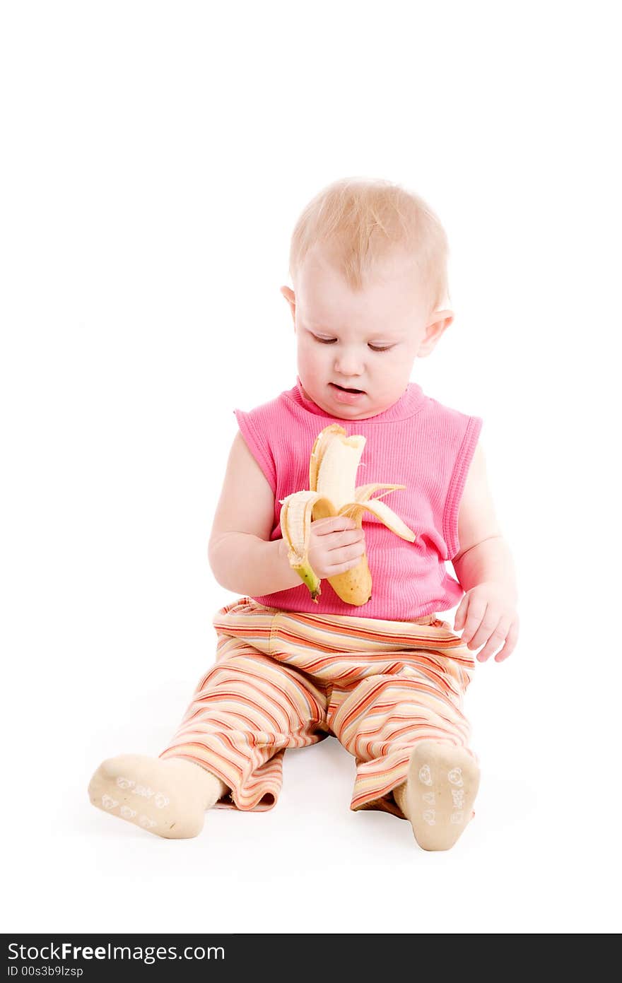 A small girl sitting on the floor and eating a banana. A small girl sitting on the floor and eating a banana