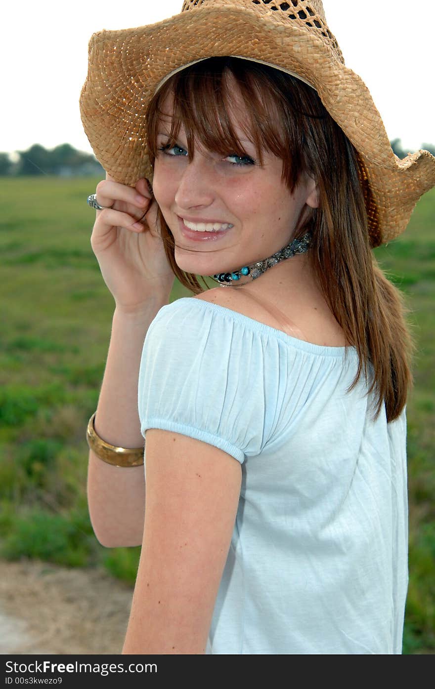 A smiling young women wearing a cowboy hat outdoors. A smiling young women wearing a cowboy hat outdoors