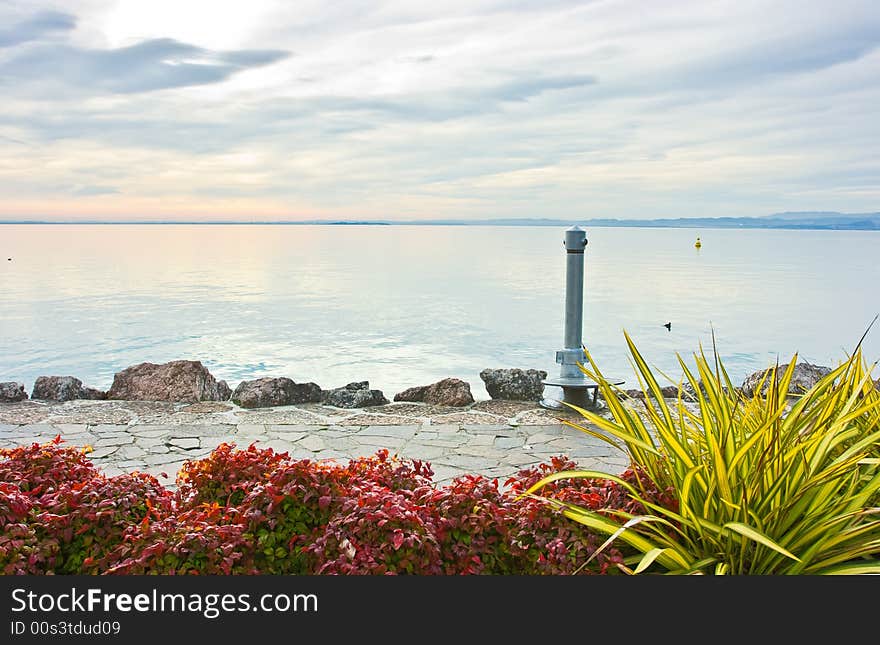 Cloudy drammatic sunset over lake Garda renders colors pastel and scenery serene