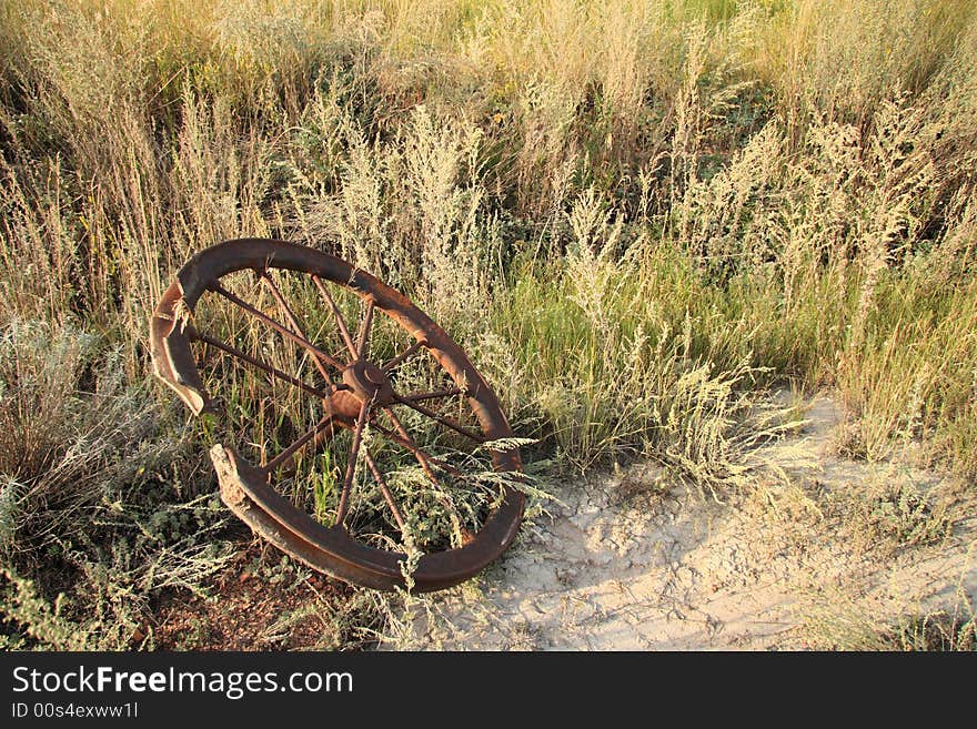 A rusty old steel pulley laying in the arid bush. A rusty old steel pulley laying in the arid bush