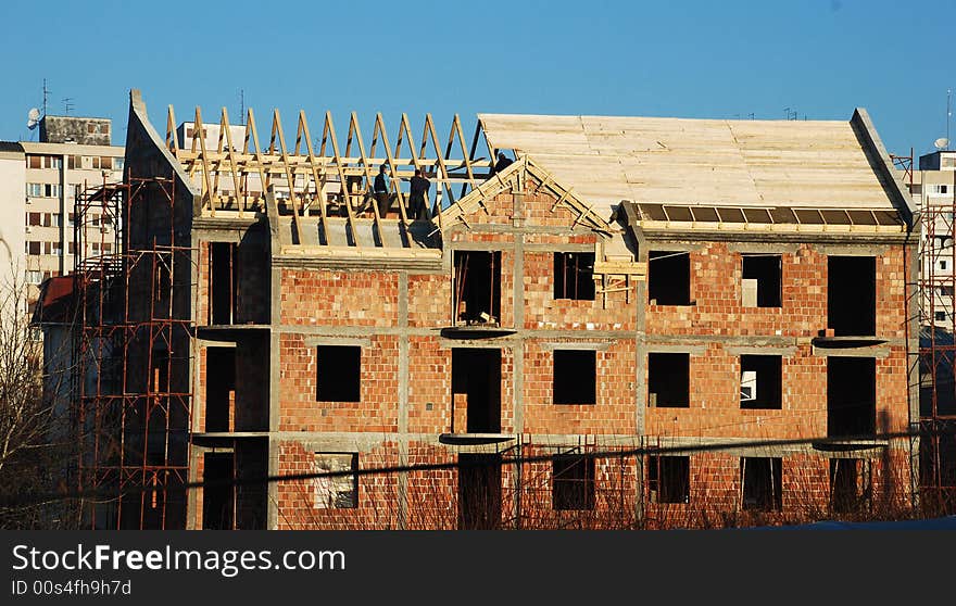 Brick building with wooden roof and workers over blue sky. Brick building with wooden roof and workers over blue sky