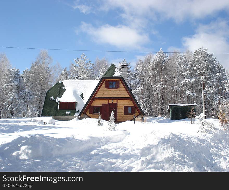 Wooden cottage hidden in the forest between the snow covered pine trees. Wooden cottage hidden in the forest between the snow covered pine trees