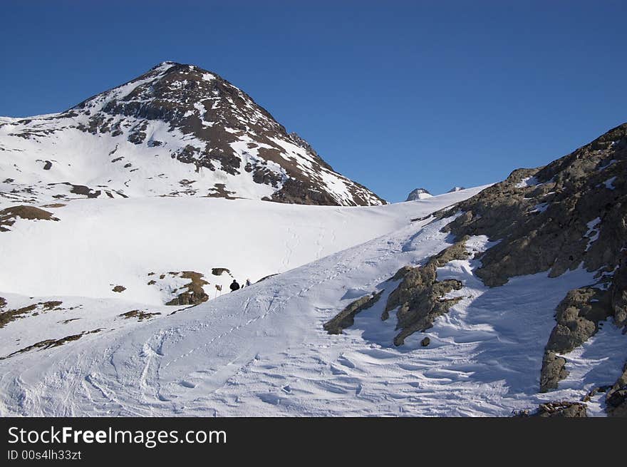 A panoramic view on Alps snow winter mountains chain under blue sky. Horizontal. A panoramic view on Alps snow winter mountains chain under blue sky. Horizontal.