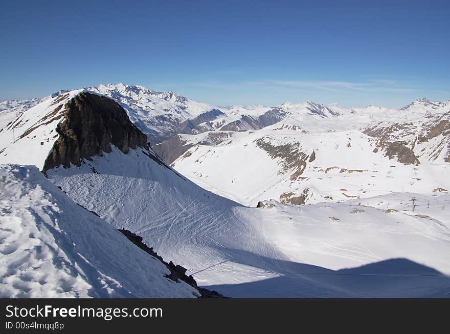 A panoramic view on Alps snow winter mountains chain under blue sky. A panoramic view on Alps snow winter mountains chain under blue sky.