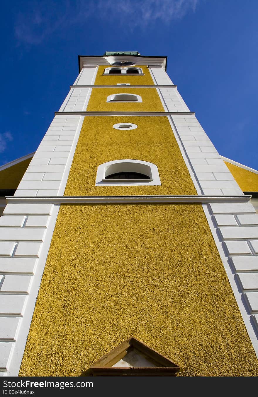 Yellow and white bell tower against deep blue sky. Yellow and white bell tower against deep blue sky