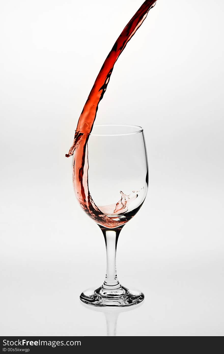 Red wine being poured into a wine glass. Red wine being poured into a wine glass.