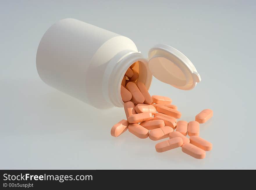 Medicine pills with a white bottle on a grey background. Close-up